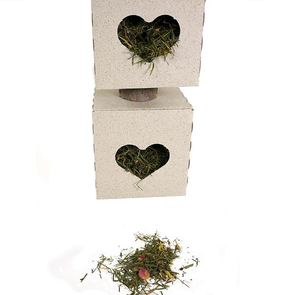 Two stone blocks with heart-shaped cutouts filled with hay on a white background