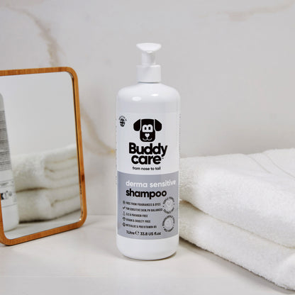 Buddy Care derma sensitive shampoo bottle on a white surface with towels and a mirror in the background.