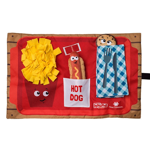 Toy hot dog set with bun, mustard, napkin, and cutlery on a red tray with a wooden border.