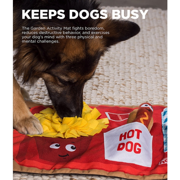 Dog playing with a toy on a mat labeled 'Hot Dog' with text about keeping dogs busy.