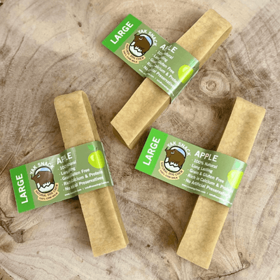 Large apple-flavour Yak Snack dog chews on wooden surface
