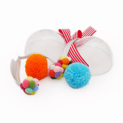 Colourful cat toy bauble opened to reveal three soft pom-pom toys in blue, orange, and multicolour, with festive red ribbon—ideal Christmas gift for cats or small pets.