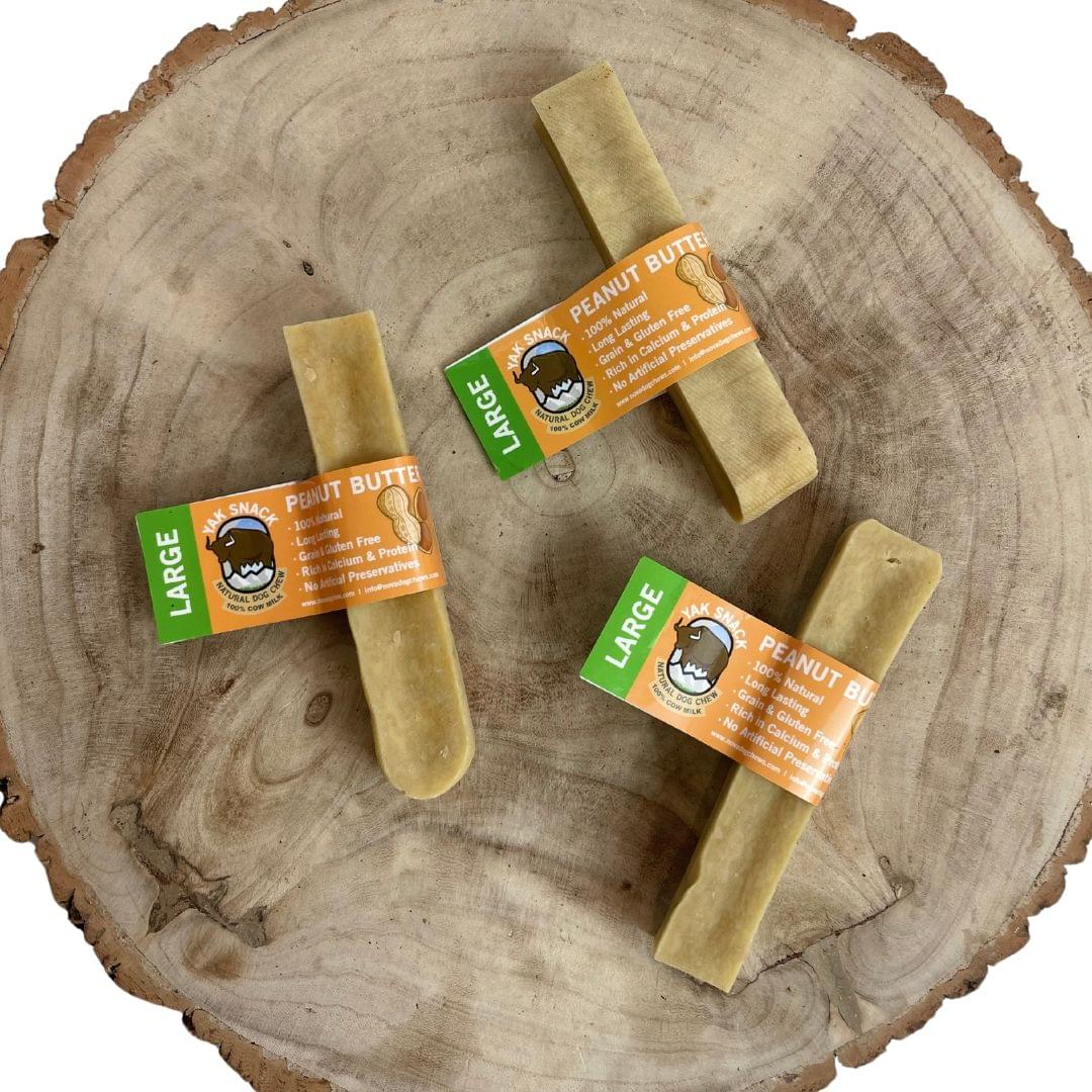 Large peanut-butter Yak Snack dog chews on wooden surface