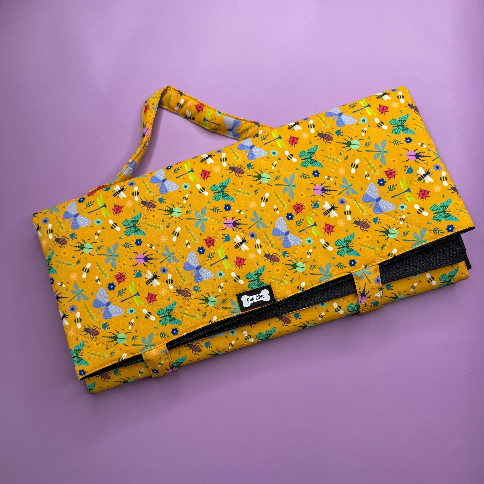 Folded Summer Buzzin’ Dog Settle Mat showing carry handle and compact size.