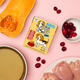 Pet supplement drink mix package with butternut squash, cranberries, and chicken on a pink background.