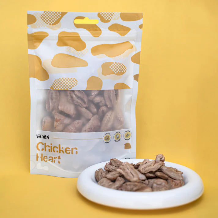 Bag of Waita Chicken Heart treats with treats on a plate against a yellow background