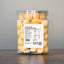 Jar of freeze-dried quail egg yolks with a label on a wooden surface and gray background