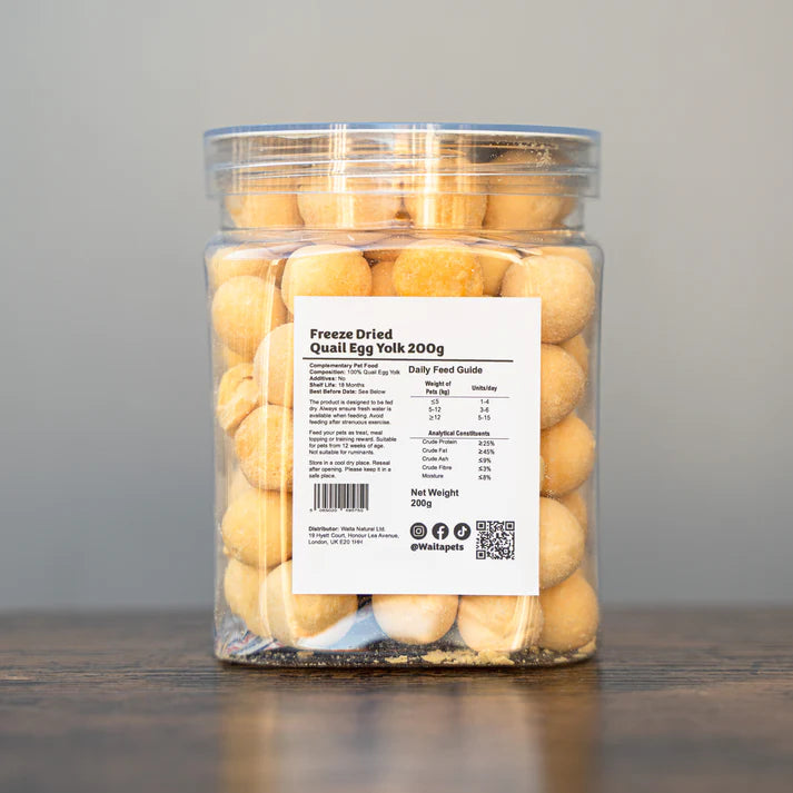 Jar of freeze-dried quail egg yolks with a label on a wooden surface and gray background