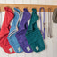 Four Ruff and Tumble dog drying coats hanging on pegs in red, blue, purple, and green, made from super-absorbent cotton towelling, perfect for post-walk drying and warmth, available at Amy’s Pet Supplies.