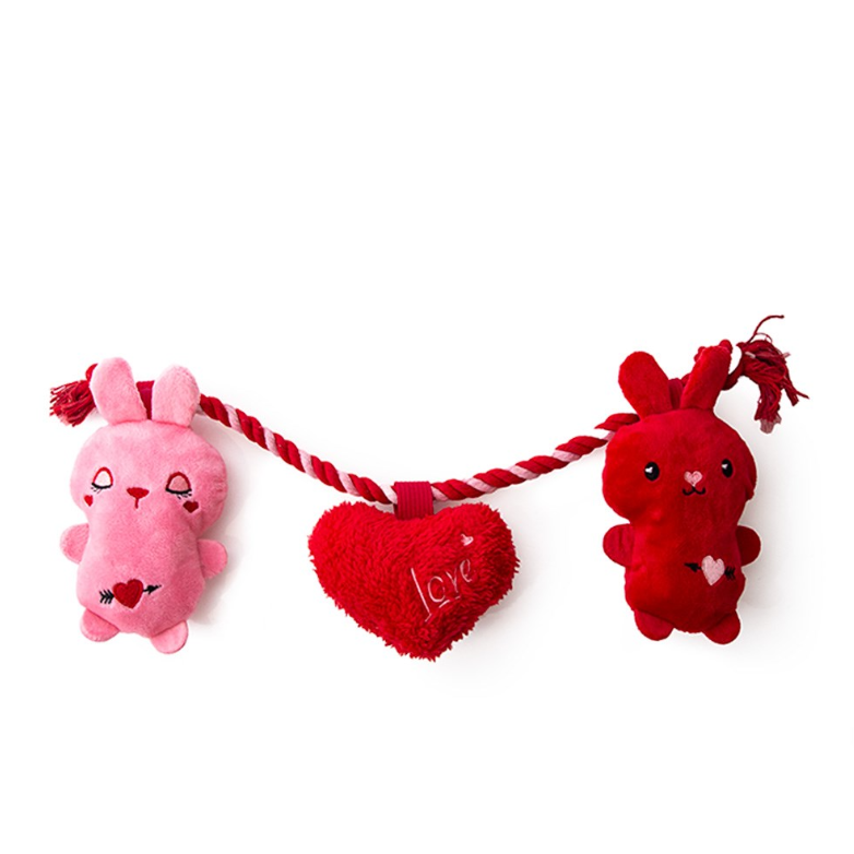 Two plush Dog toys, one pink and one red, with a heart-shaped 'Love' pillow on a white background.