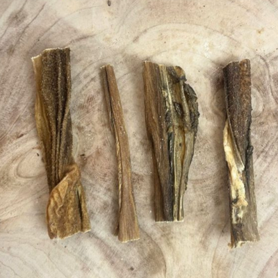 Selection of dried beef tripe dog chews laid out on wood, showcasing natural texture