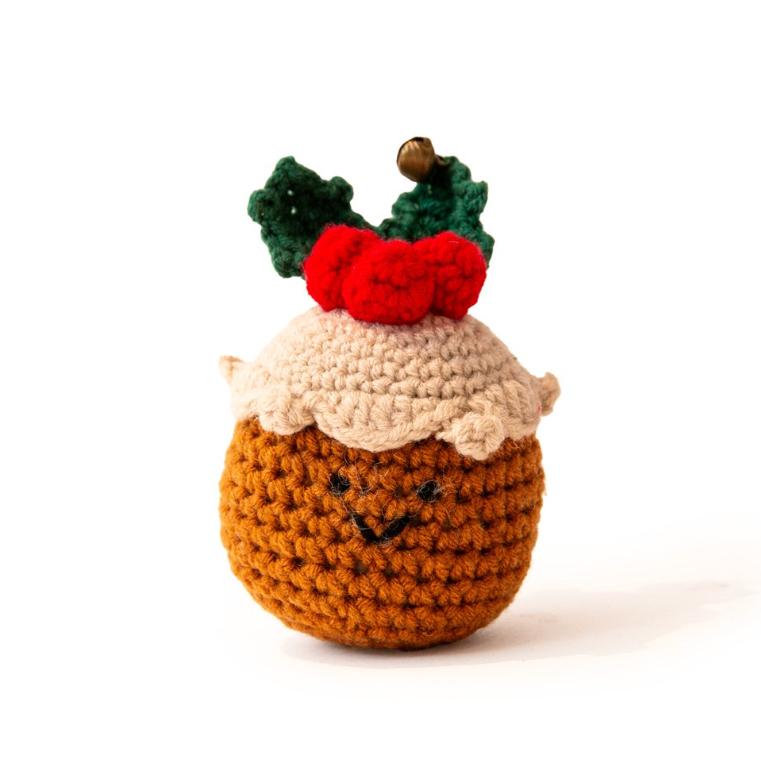 Great&Small Cosy Winter Wishes knitted Christmas pudding cat toy with a brown body, cream icing, red berries, green holly leaves and a small bell.