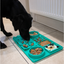 Black dog eating from a teal Örva Suction Cup Slow Feeding Station filled with different foods