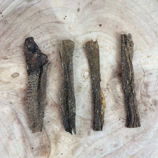 Four natural lamb tripe dog chew pieces arranged on a wooden board, shown as a sample of the 1kg pack