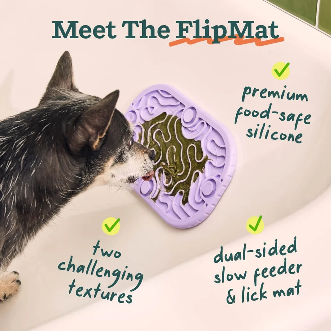 Small dog licking spreadable food from purple Woof FlipMat Mini enrichment mat